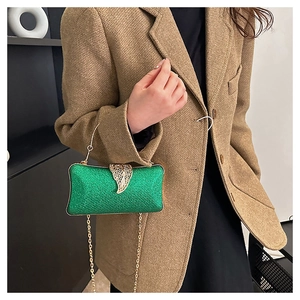 Macro shot of green textured evening clutch featuring a gold leaf lock and chain strap