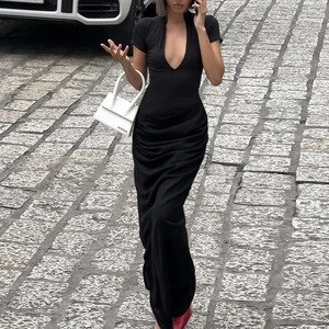 Detail shot of a sexy black deep V-neck slim-fit maxi dress featuring elegant pleats