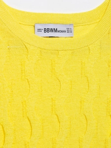 Detalle del cuello de punto amarillo con diseño desgastado y etiquetas de marca BBWM