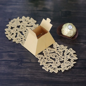 Detail of laser-cut butterfly candy box in gold pearlescent paper on wood background