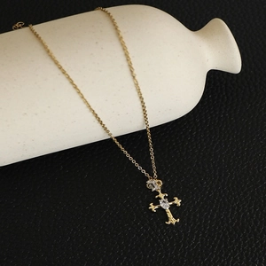 Close-up of gold cross pendant with oval cubic zirconia on stainless steel chain