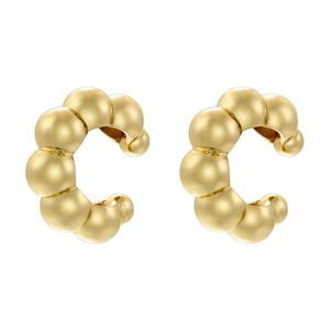 Macro shot of polished gold-tone C-shaped beaded ear cuffs with high gloss metallic finish