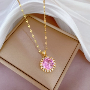 Detail of gold necklace with round pink gemstone and pavé diamonds on white silk