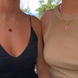 Layered gold chain necklaces with red and pink floral pendants on models