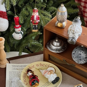 Detailed view of astronaut and UFO Christmas ornaments on a festive pine tree branch