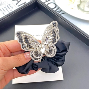 Detail of elegant black satin scrunchie with a silver butterfly and crystal rhinestones