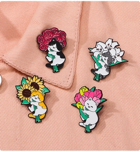 Set of four cartoon cat floral pins displayed on a pink denim collar showing usage