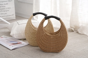 Detail of handmade woven straw handbags in beige and brown with black top handles