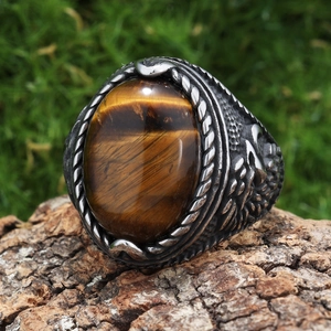 Macro shot of eagle-style ring with oval tiger eye stone on natural bark background