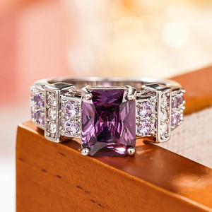 Macro view of emerald-cut purple gemstone ring with ornate micro-pave diamond setting