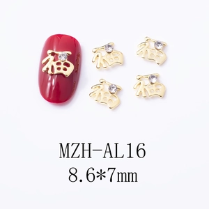 Close-up of golden Fu character nail charms with rhinestones on red manicured nails