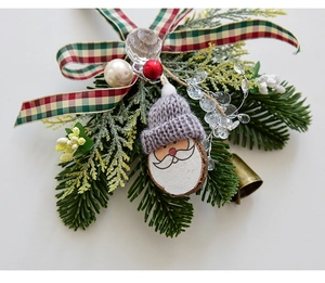Detail of Christmas ornament with Santa plaque, pine needles, plaid ribbon and small bell