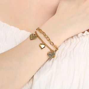 Detail of layered gold stainless steel bracelet featuring heart pendants and bead chain