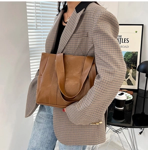 Close-up of brown PU leather tote bag styled with a professional plaid blazer outfit