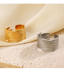 Detailed close-up of 18K gold and silver feather rings on stone and satin base
