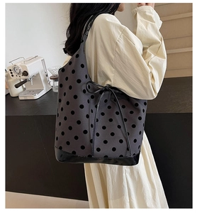 Close-up of a large polka dot bucket bag featuring a patent leather base and bow detail