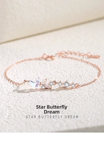 Détail d'un bracelet en or rose avec papillon iridescent et charmes d'étoiles en zircon