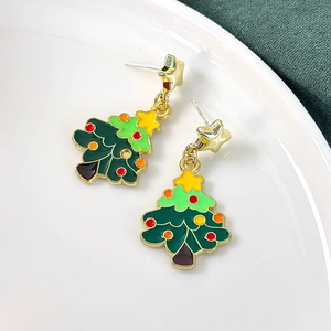Detail view of cute green Christmas tree earrings with star decor on white plate