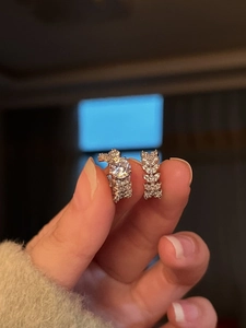 Detailed close-up of a zircon-encrusted silver ear cuff held against a dark background