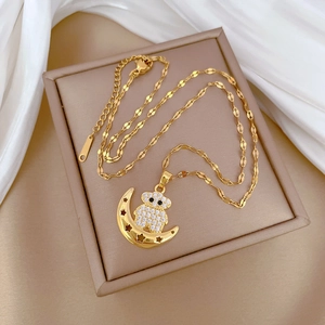 Macro detail of gold bear and crescent moon necklace with rhinestones on silk