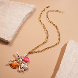 Gold ocean necklace with starfish shell and pearls on beach-style sand stones
