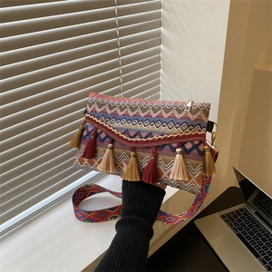 Detail of bohemian woven crossbody bag with colorful tassels and jacquard strap