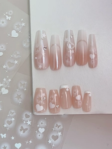 Macro view of nude pink gradient coffin press-on nails with 3D hearts and butterfly charms