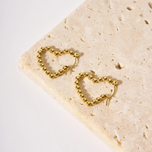 Dettaglio di orecchini a cerchio a cuore con perle placcati in oro 18K su pietra