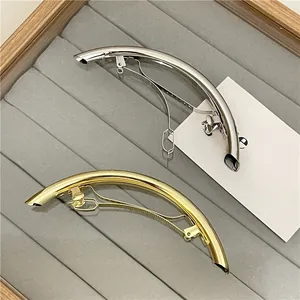 Close-up of minimalist gold and silver metallic curved hair clips on a velvet tray