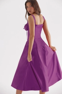 Detail of a purple midi dress showing the back lace-up design and flowing silky fabric