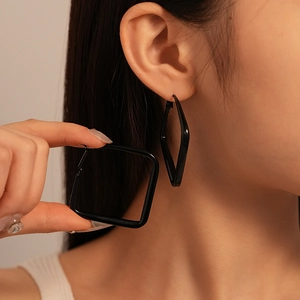 Close-up of a large black geometric square earring with a glossy finish on a model