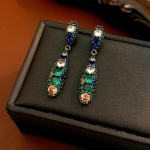 Détail macro de boucles d'oreilles goutte vintage avec pierres multicolores sur cuir noir