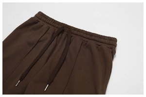 Detail of high-waist brown joggers with elastic waistband and metal tip drawstring