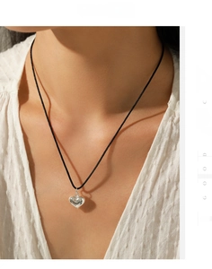 Detail of s925 silver heart pendant on a black cord necklace worn by a model