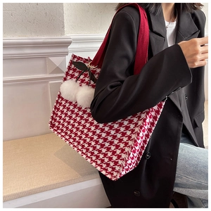 Detail of red houndstooth canvas tote bag with cherry pom pom charm and webbing strap
