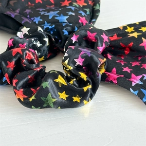 Macro shot of satin scrunchie with colorful metallic stars and smooth fabric pleats