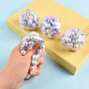 Set of 4 colorful squeeze stress relief balls with pearl beads on a light blue table