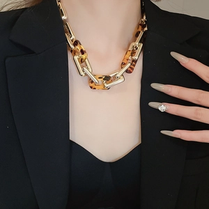 Dettaglio della collana a catena leopardata vintage con maglie d'oro su un blazer nero