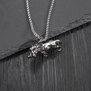 Detailed view of the punk lion head pendant on a silver box chain over dark slate