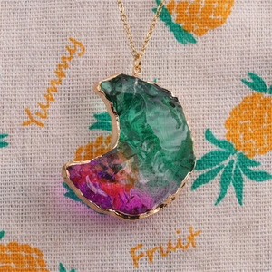 Gros plan d'un pendentif lune en acier inoxydable avec résine colorée et chaîne dorée