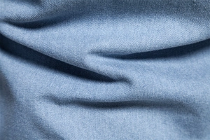 Macro du tissu en sergé bleu clair et des plis doux sur cette chemise en denim