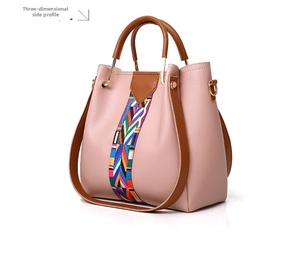 Side view of pink leather handbag with brown handles and woven geometric strap detail