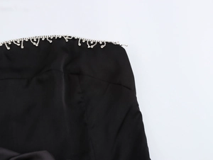 Dettaglio del bordo decorato con strass sull'abito da sera in raso nero con fiori 3D