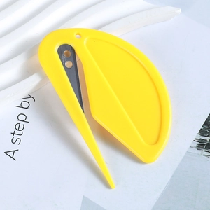 Mini yellow multifunctional utility cutter and letter opener on a book surface