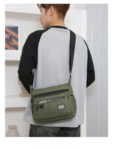 Detail of military green crossbody bag with multi-zipper pockets and adjustable strap