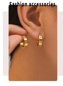 Macro detail of 18K gold plated C-shaped earrings with inlaid zircon on earlobe