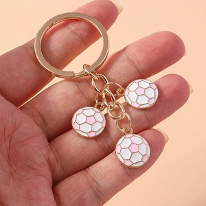 Handheld golden keychain featuring three pink and white miniature football pendants
