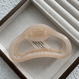 Detailed macro view of a large translucent peach jelly hair claw clip on a soft beige background