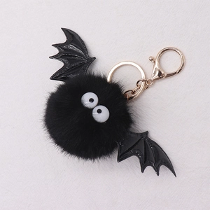 Detail of black faux mink bat keychain with plush ball, patent wings and gold ring