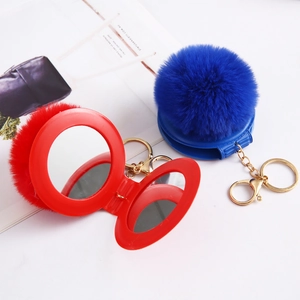 Macro shot of faux rabbit fur pom pom compact mirrors with golden metal keychain clips